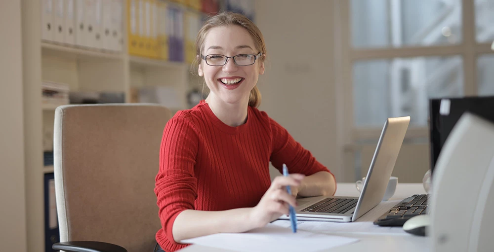 gen z college student smiling while working on financial literacy education assignment at desk