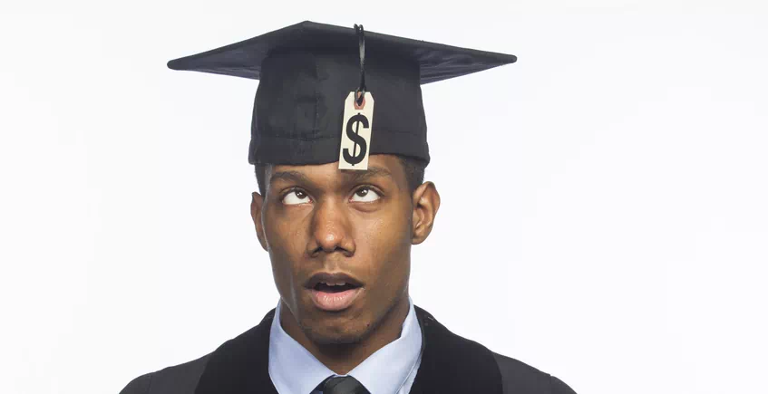 Man wearing graduation cap that has dollar sign as a tassle