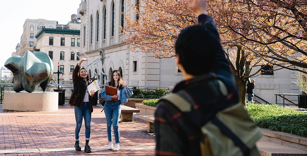 college students waving to each other in courtyard