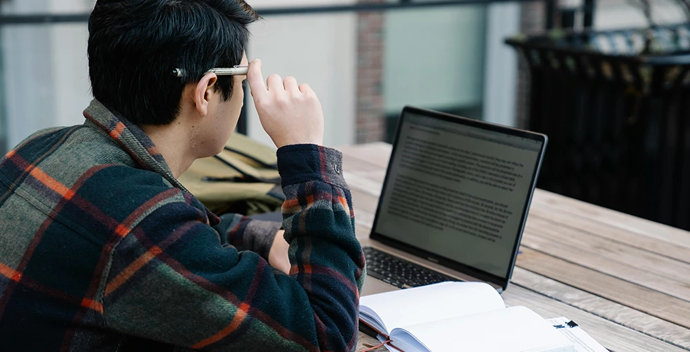 photo of a college student reading on his laptop