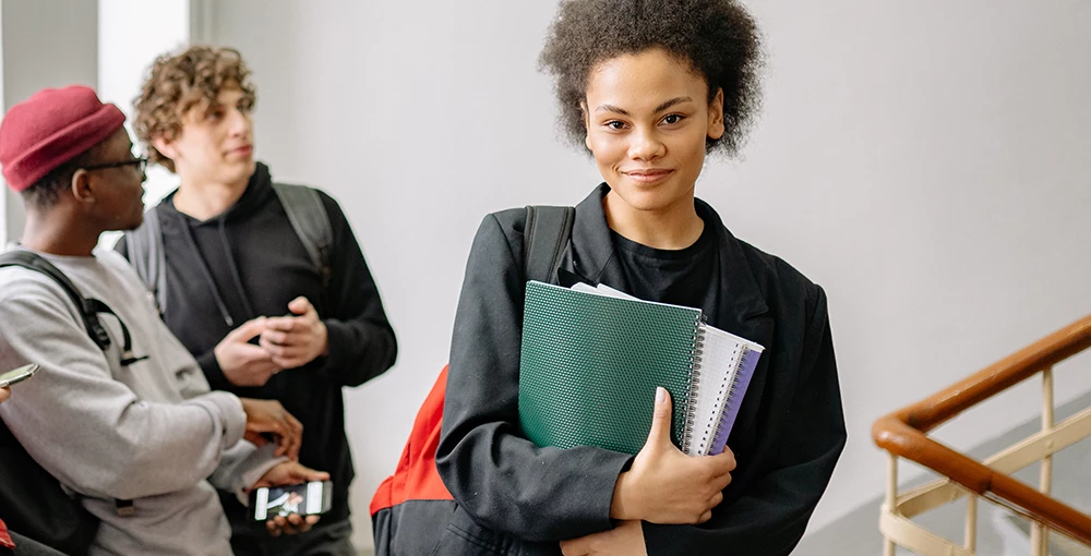 college student smiling while holding her notebooks