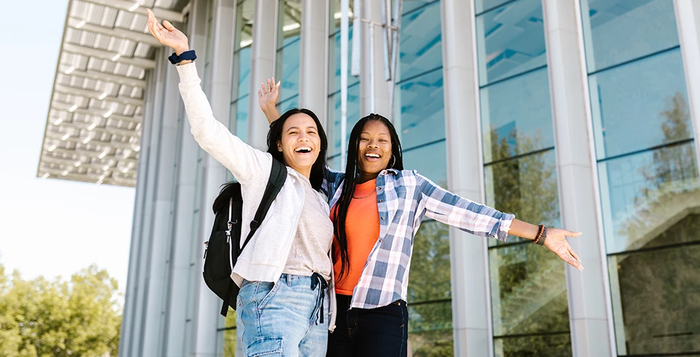 college students posing with their hands raised because they've improve their financial wellness