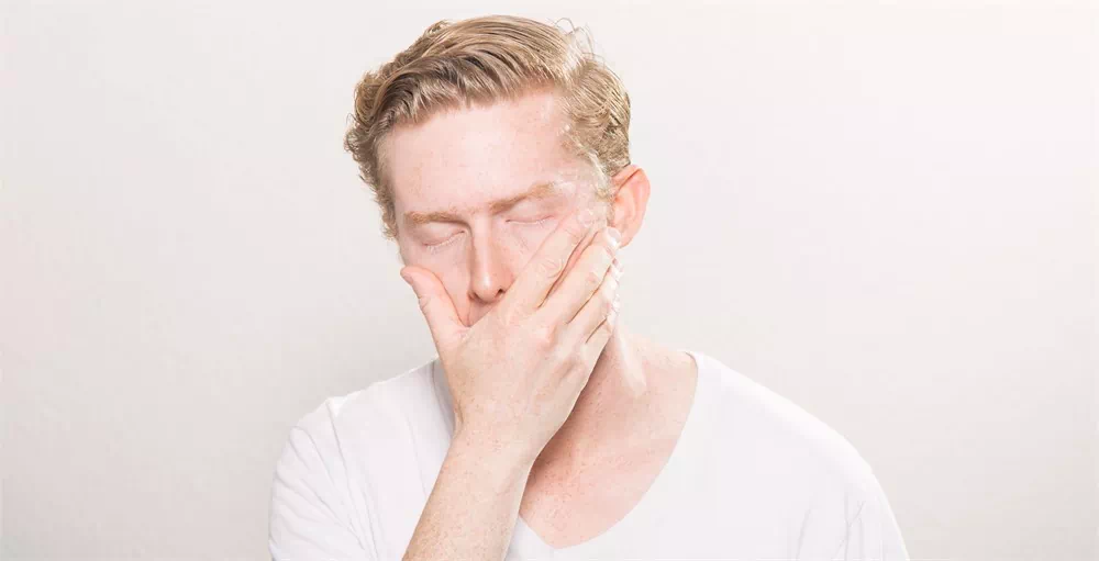 employee suffering from financial stress covering face on white background