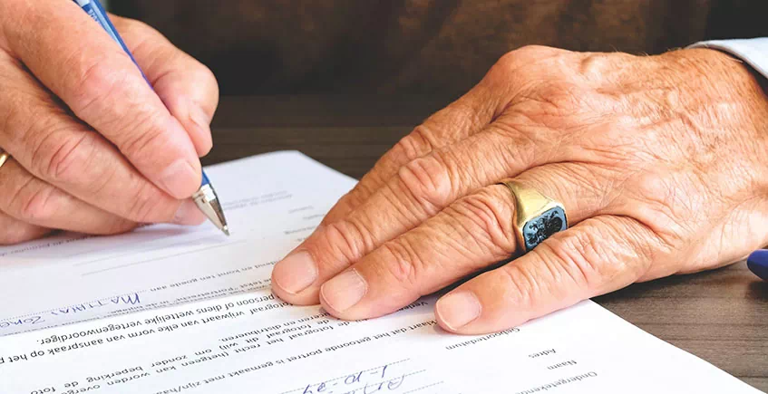 Elderly man's hands signing a financial contract