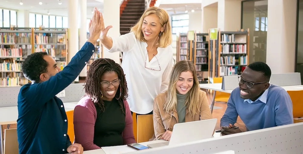 College students gathered in a library at a desk learning how they can decrease the amount of student loans they borrow to pay for a semester of school