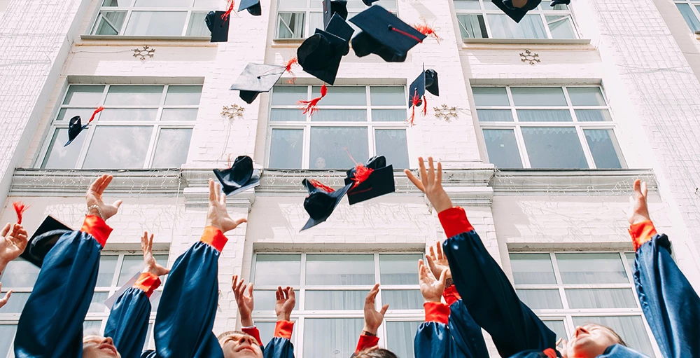 group of college graduates throwing their caps in the air