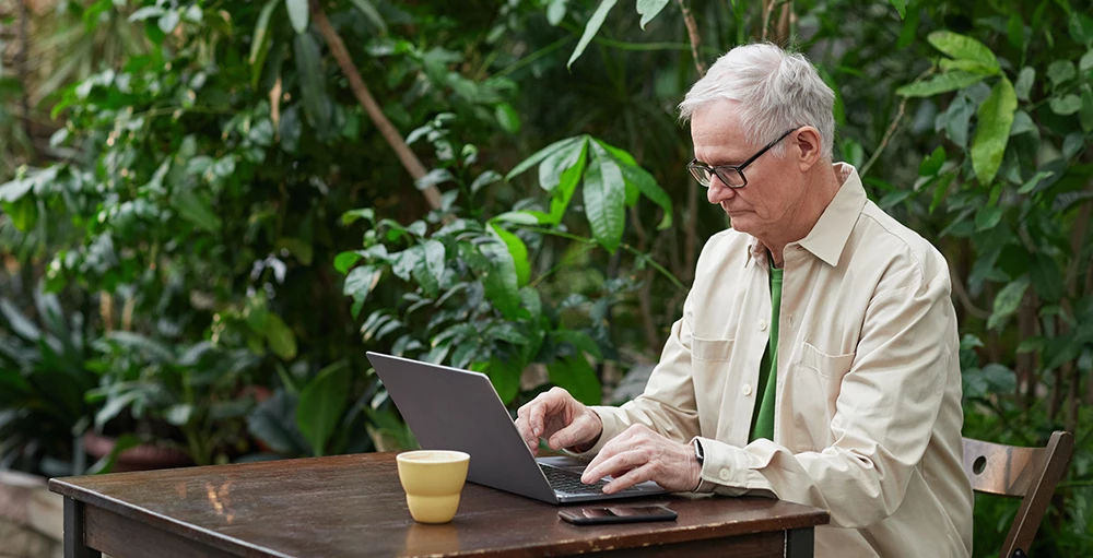older man researching social security and financial wellness on laptop
