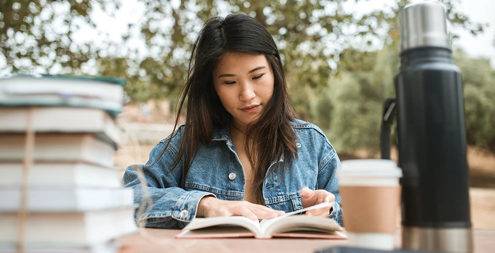 college student reading books while drinking coffee