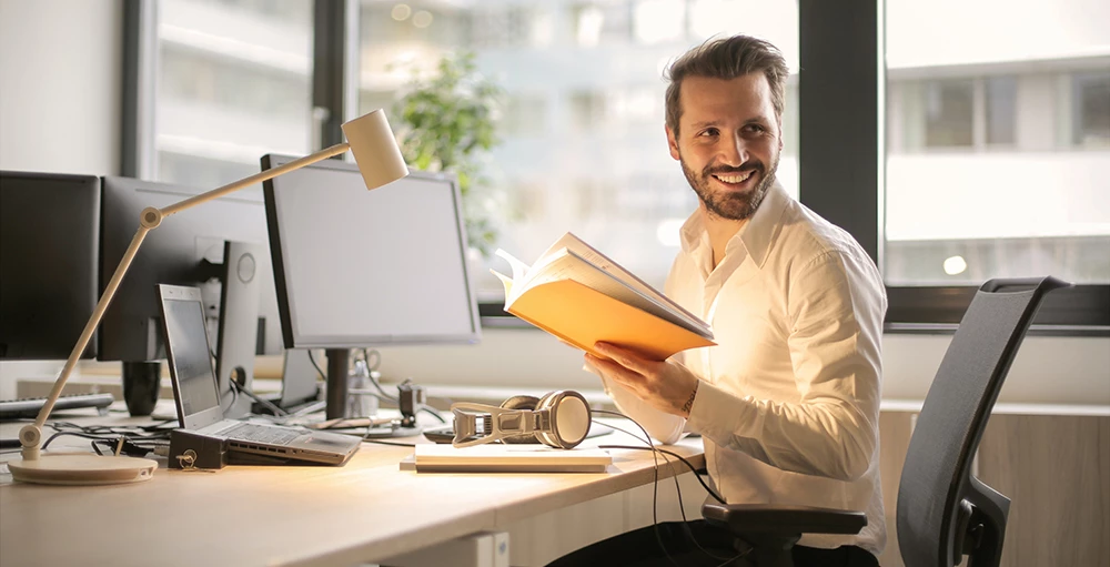 happy employee holding book and smiling at the office