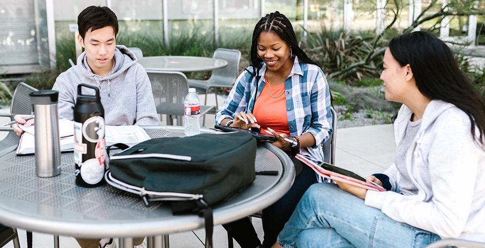 college students studying together at picnic table