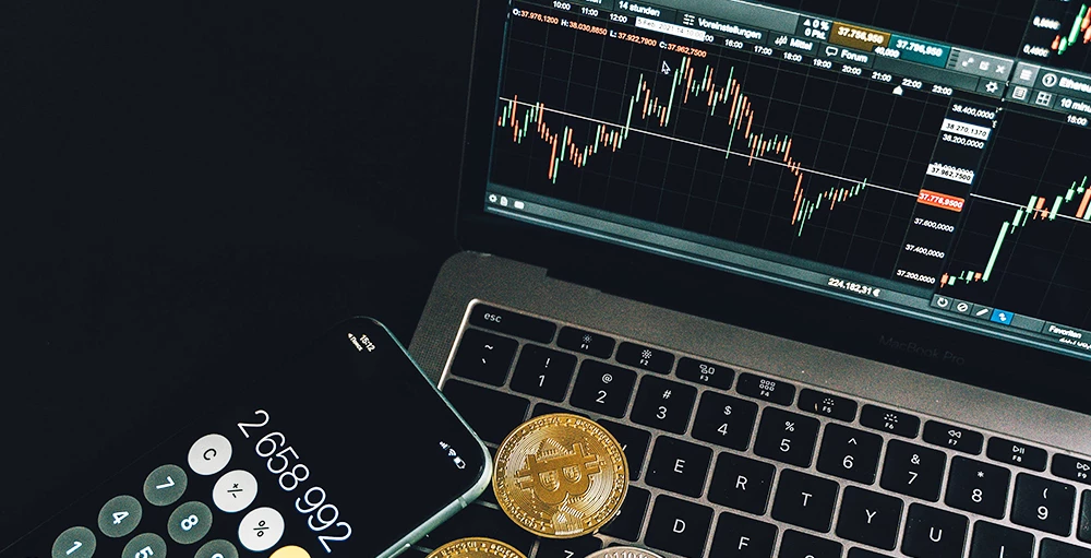 gold coins and crypto stats on laptop