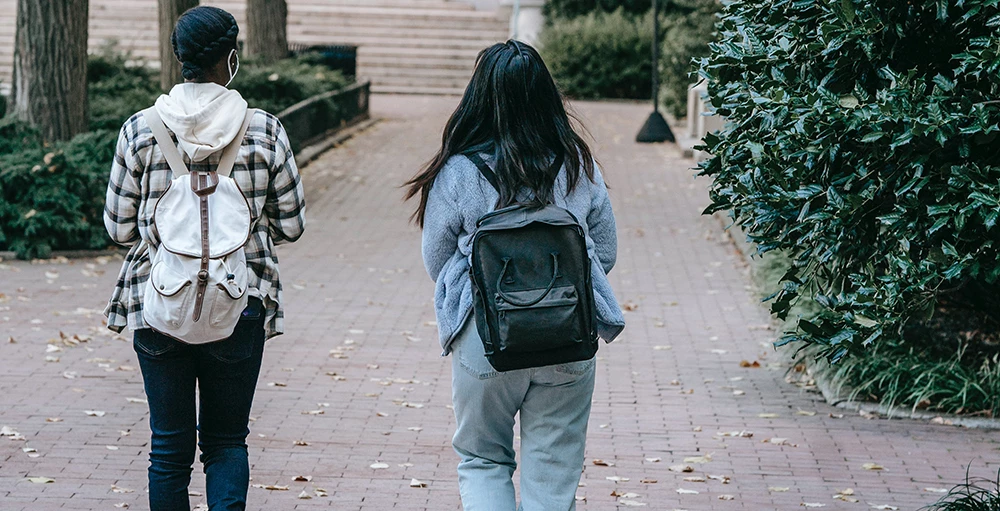 college students with backpacks walking on sidewalk