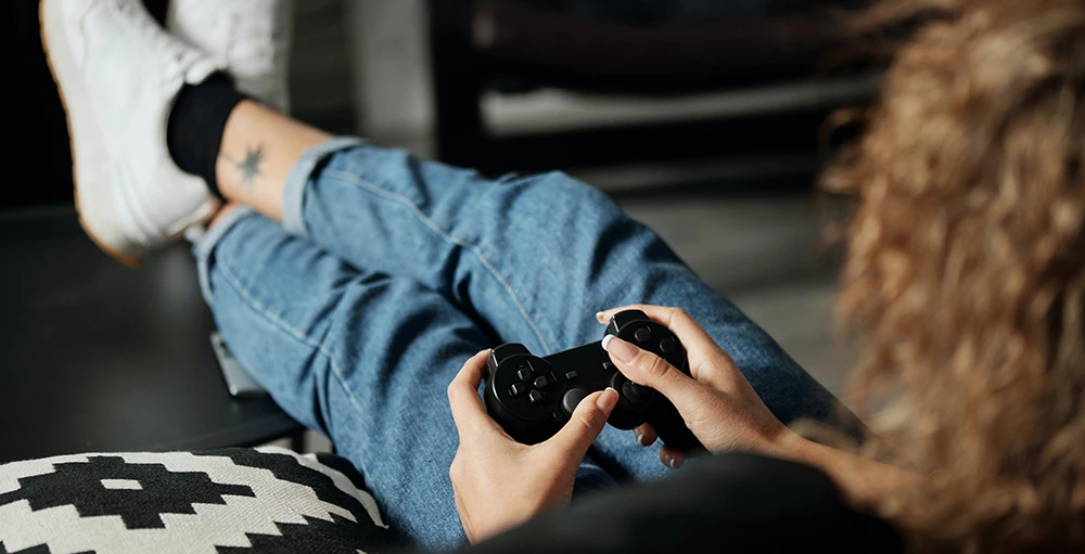 Person in Blue Denim Jeans Holding Black Game Controller