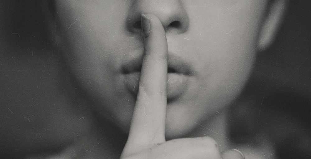 Woman putting her finger to her lips to symbolize a secret