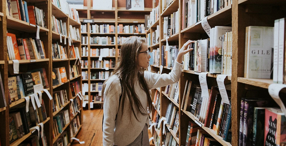 student browsing library shelves for books on financial wellness