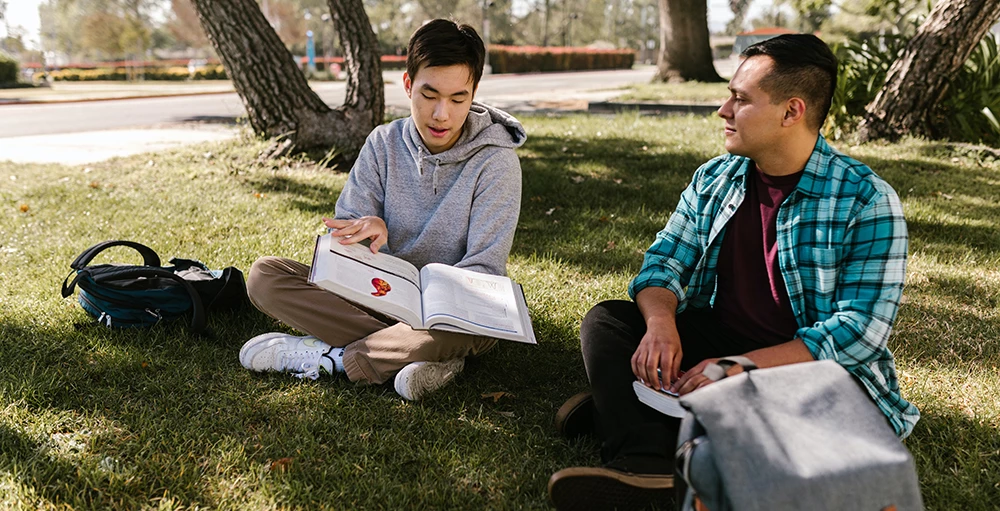 college students sitting on the grass while studying financial wellness