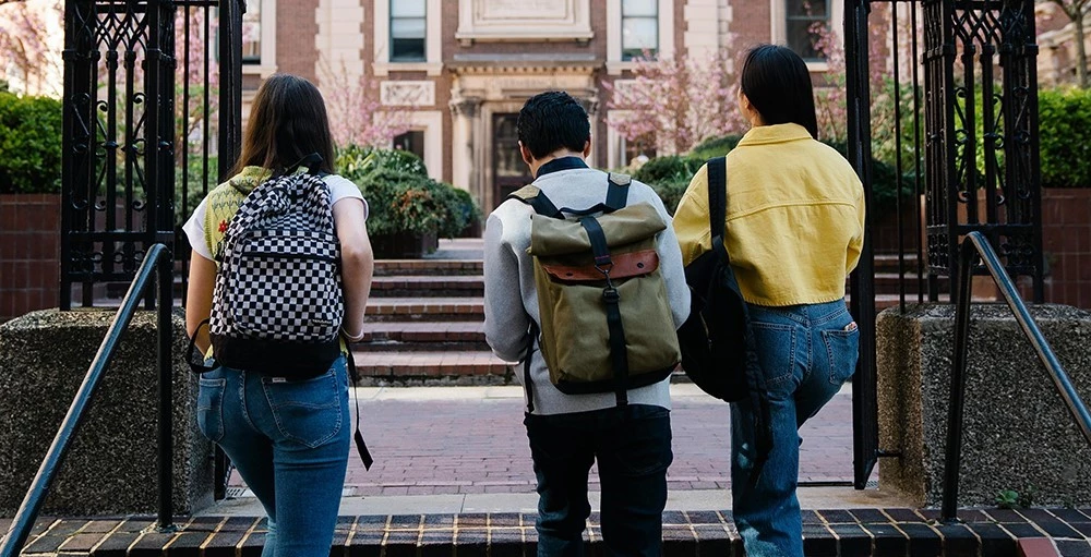 back view of college students walking into a campus