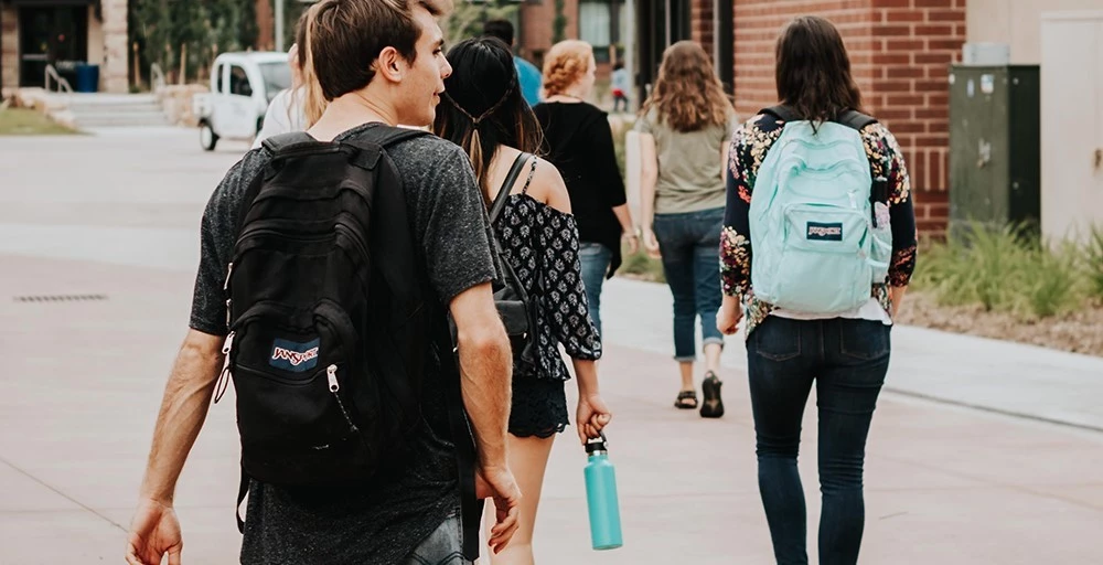 a group of students walking on college campus