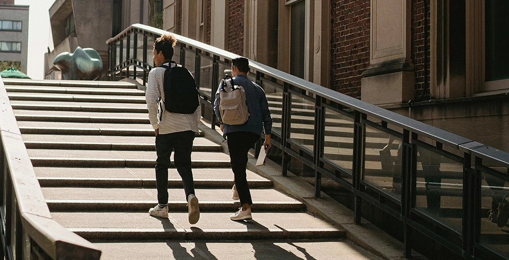 college students walking upstairs on campus on a sunny day