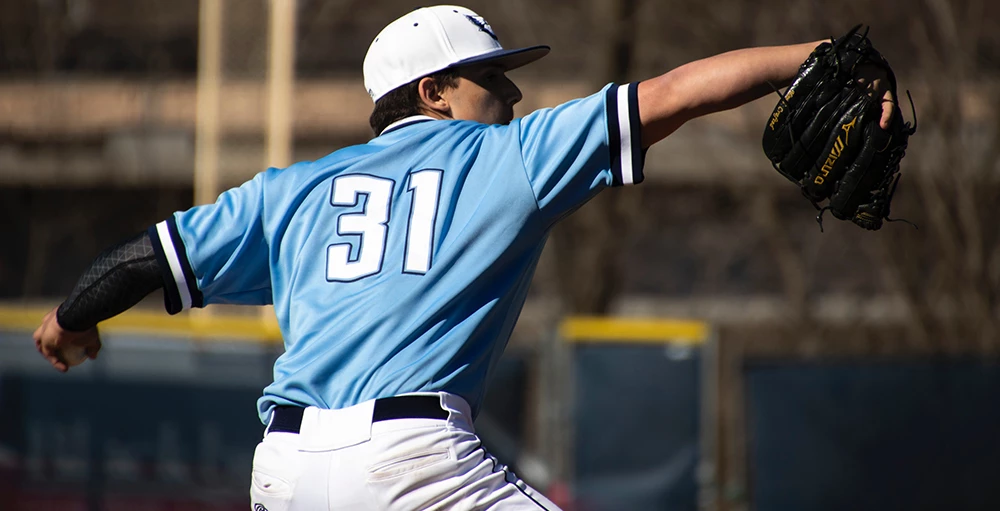 college athlete in blue and white jersey playing baseball